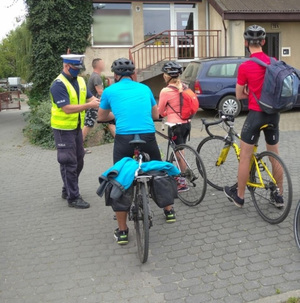 Policjant przekazuje ulotki rowerzystom