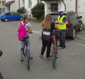 Policjant przekazuje ulotki rowerzystom