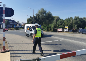 policjant kontroluje pojazd przy przejeździe kolejowym