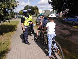 Policjanci rozdają młodym rowerzystom opaski odblaskowe