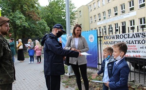 Policjant przekazuje ulotkę dziecku