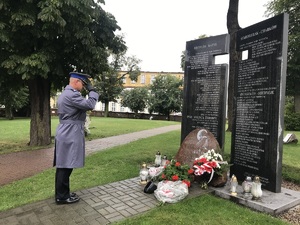 Policjant salutuje w stronę pomnika