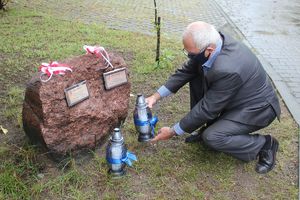 Mężczyzna kładzie znicz przy pomniku