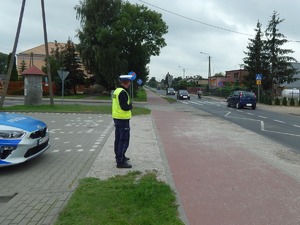 Policjant RD stoi na chodniku za nim radiowóz