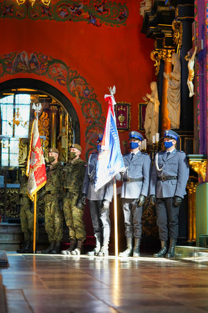 żołnierze i policjanci stoją w kościele trzymając sztandary