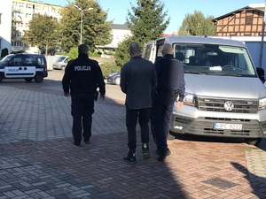 Policjanci prowadzą podejrzanego 43-latka, by przekonwojować go za kraty