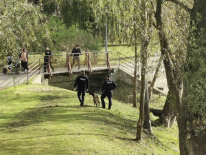 Patrol z psem w okolicach kładki nad rzeką.