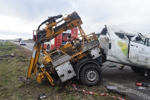 Widok na rozbitą przyczepkę samochodową wraz z maszyną