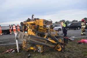 Widok na rozbitą przyczepkę samochodową wraz z maszyną