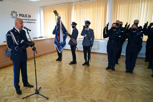 Komendant czyta rotę ślubowania. obok stoją policjanci, którzy ślubują