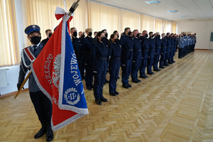 policjanci stoją w szeregu i powtarzają rotę ślubowania. A przodu stoją trzej policjanci z pocztem sztandarowym