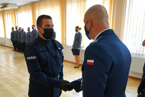 Komendant gratuluje i wręcza akt ślubowania policjantowi