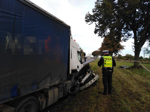 Policjant stoi nad rozbitym samochodem