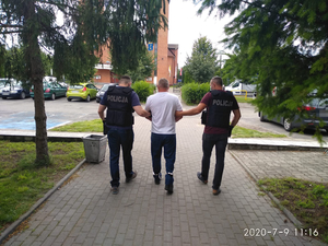 Policjanci prowadzą zatrzymanego mężczyznę