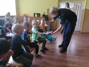 Policjantka zakłada odblask na rękę dziecka