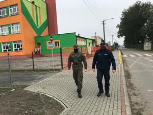 Policjant i żołnierz podczas patrolu osiedla.