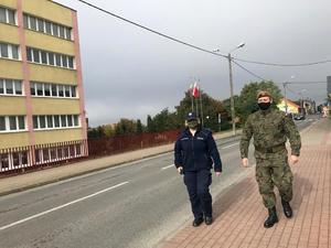 Policjantka i żołnierz podczas pieszego patrolu ulicy.