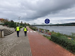 Policjant i strażnik miejski idą bulwarem nad Wisłą.