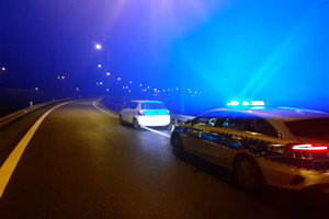 Policjanci kontrolują zatrzymany na autostradzie samochód