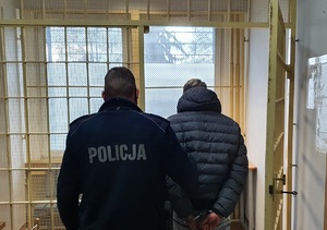 Zatrzymany mężczyzna stojący razem z policjantem.