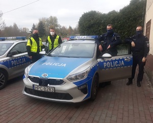 czterech policjantów pozuje do zdjęcia przy radiowozie