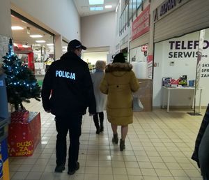 Policjant i dwie kobiety chodzą alejkami galerii