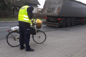 Policjant przekazuje elementy odblaskowe rowerzyście