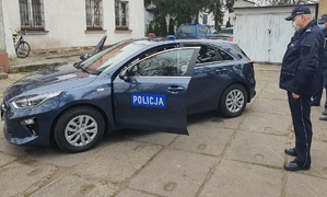 Policjant stoi przy nieoznakowanym radiowozie