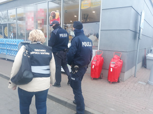 Policjanci i kobieta w kamizelce z napisem inspekcja sanitarna.