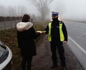 Policjant przekazuje kobiecie odblaski