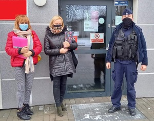 Policjant i dwie kobiety stoją przed wejściem do lokalu