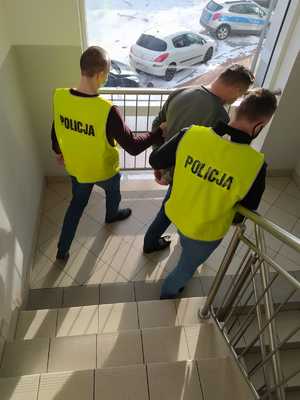 Policjanci prowadzą zatrzymanego mężczyznę