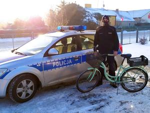 Policjant stoi obok odzyskanego roweru