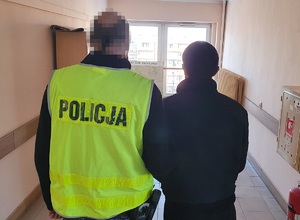 Policjant prowadzi zatrzymanego mężczynę