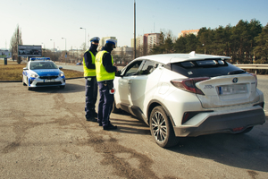 Dwóch policjantów stoi przy zatrzymanym do kontroli samochodzie