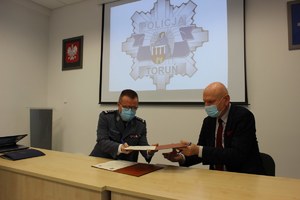 Komendant Miejski Policji w Toruniu i Prezydent Miasta Torunia wymieniają się dokumentami