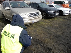 Policjant kuca przy odzyskanym samochodzie