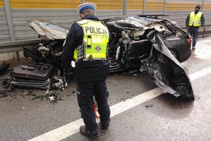 Policjant stoi nad rozbitym samochodem