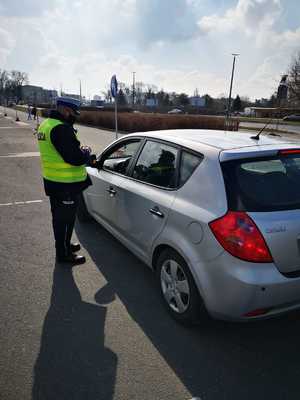 Policjant stoi przy samochodzie zatrzymanym do kontroli