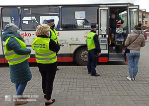Policjant i pracownicy sanepidu stoją przy autobusie