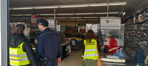 Policjant i pracownicy sanepidu wchodzą do sklepu
