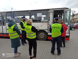 Policjant i pracownicy sanepidu stoją przy autobusie