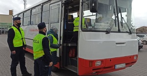 Policjant i pracownicy sanepidu stoją przy autobusie
