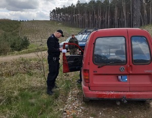 Policjant i strażnik leśny kontrolują zatrzymany w lesie samochód