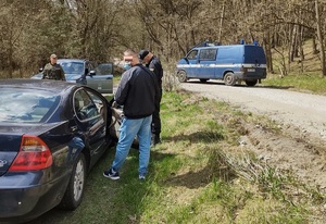 Policjant i strażnik leśny kontrolują zatrzymany w lesie samochód