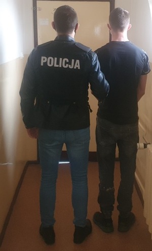 Policjant prowadzi zatrzymanego mężczyznę