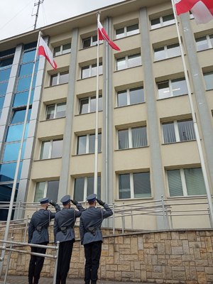 Trzech policjantów salutuje do flagi