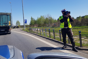 Policjant mierzy prędkość pojazdu zbliżającego się do autostradowych bramek