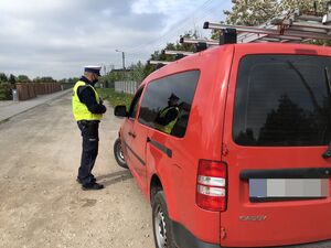 Policjant kontroluje kierowcę czerwonego Caddy