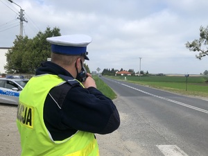 Policjant RD stoi na poboczu i mierzy prędkość radarem